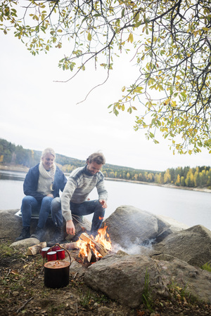 Couple Sitting Near Bonfire On Lakeshoreの写真素材
