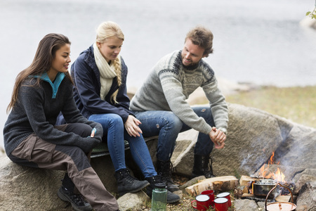 Friends Talking While Sitting On Rock During Campingの写真素材
