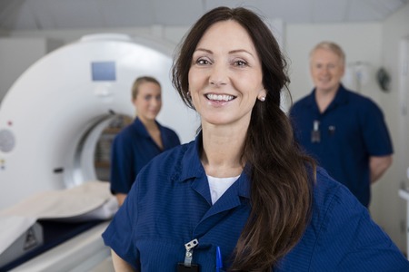Smiling Female Radiologist With Colleagues Standing By MRI Machiの写真素材