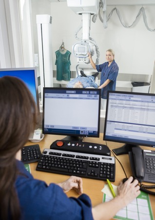 Doctor Taking Patients Xray While Coworker Using Computer At Deの写真素材