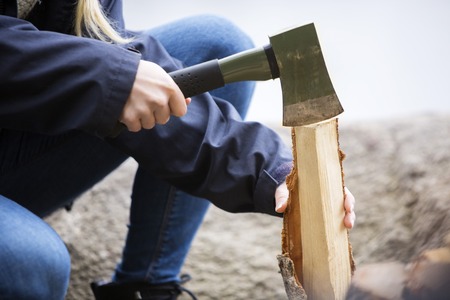 Woman Cutting Wood For Bonfire On Campsiteの写真素材