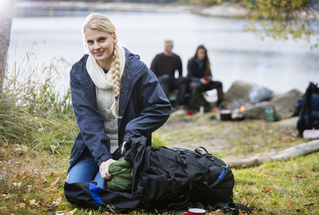 Young Woman Unpacking Backpack At Campsiteの写真素材