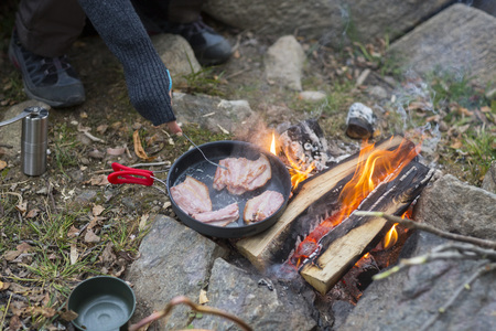 Woman Cooking Meat Over Bonfire At Campsiteの写真素材