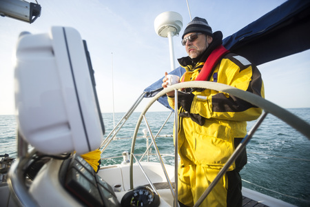 Man Holding Coffee Cup While Standing At Helm Of Sail Boatの写真素材