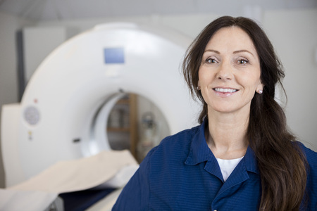 Smiling Female Professional Against MRI Machine In Hospitalの写真素材