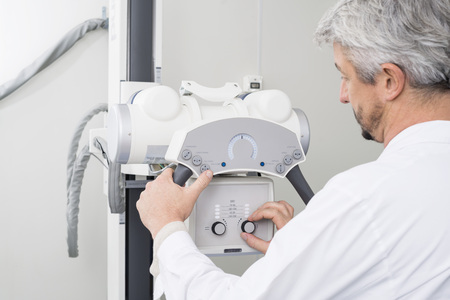 Male Radiologist Adjusting The Controls On X-ray Machineの写真素材