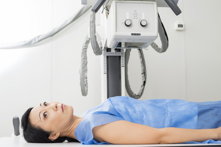 Female Patient Lying Under X-ray Device In Examination Roomの写真素材
