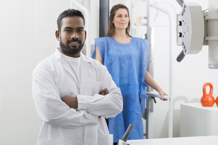 Male Radiologist Standing Arms Crossed In Examination Roomの写真素材