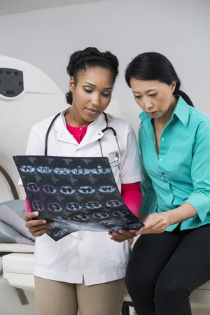 Serious Doctor And Woman Looking At X-ray Report In Hospitalの写真素材