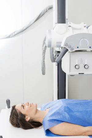 Female Patient Lying Under X-ray Machine In Examination Roomの写真素材