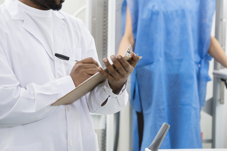 Midsection Of Male Radiologist Writing On Clipboard In Hospitalの写真素材