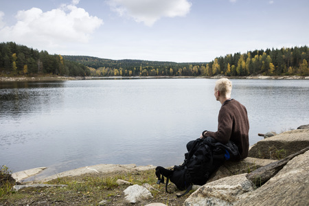 Man Sitting On Rock While Enjoying Lake Viewの写真素材