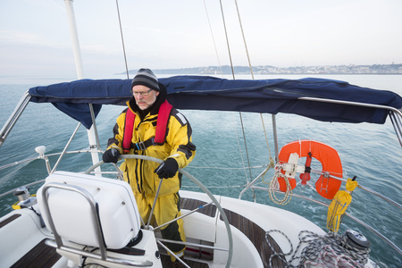 Man Wearing Waterproof Jacket While Steering Yacht In Seaの写真素材