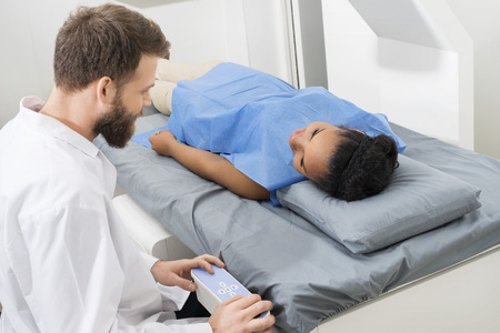 Doctor Examining Female Patient Lying On Bed In Hospitalの写真素材