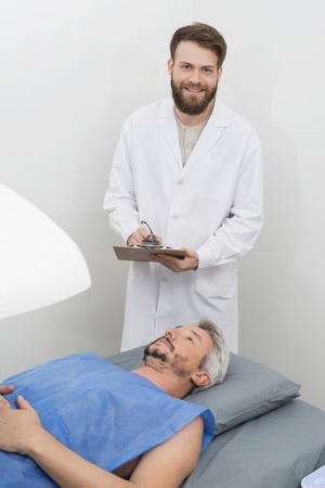 Doctor Writing On Clipboard While Patient Undergoing Bone Densitの写真素材