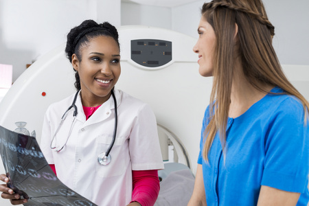 Female Doctor Holding Chest X-ray While Looking At Patientの写真素材