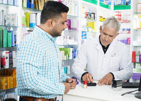 Pharmacist Stamping Paper While Customer Standing At Counterの写真素材