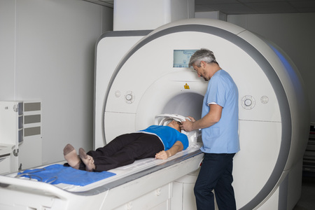 Doctor Fixing Mask To Female Patient Lying CT Scan Machineの写真素材