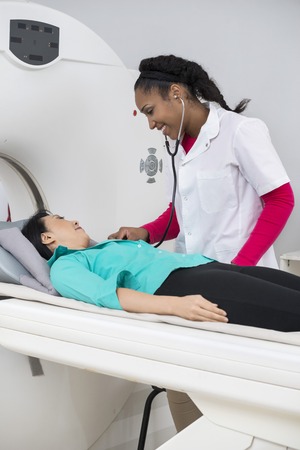 Doctor Examining Woman With Stethoscope Before CT Scanの写真素材