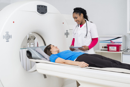 Female Doctor Looking At Patient Undergoing MRI Scanの写真素材