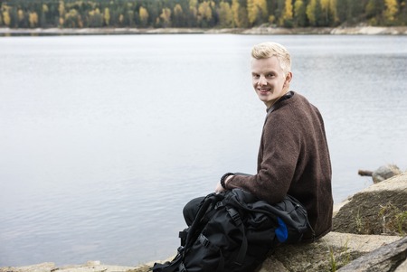 Happy Male Hiker Sitting On Lakeshoreの写真素材