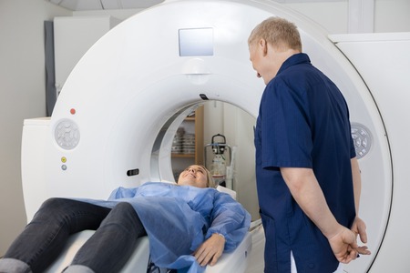 Radiologist Looking At Female Patient Lying On MRI Machineの写真素材