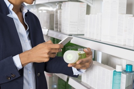 Businesswoman Scanning Products Barcode Through Smart Phoneの写真素材