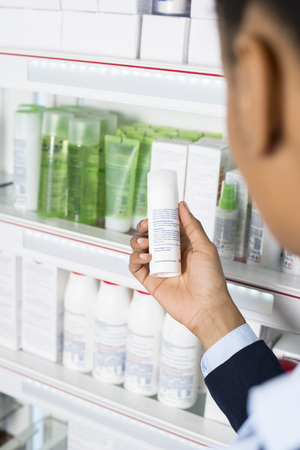 Businesswoman Reading Instructions On Medicine Bottle At Pharmacの写真素材