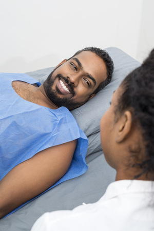 Smiling Young Patient Looking At Radiologist During X-ray Scanの写真素材