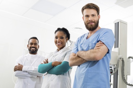 Smiling Radiologists Standing Arms Crossed In Examination Roomの写真素材