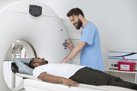 Young Doctor About To Start CT Scan On Man In Hospitalの写真素材