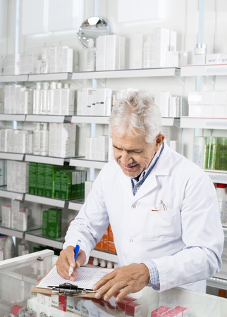 Chemist Writing On Clipboard In Pharmacyの写真素材