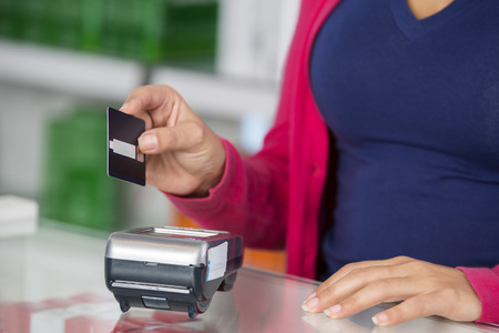 Customer Holding Credit Card Over Reader In Pharmacyの写真素材
