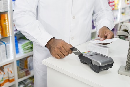 Midsection Of Chemist Holding Receipt While Swiping Credit Cardの写真素材