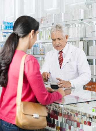 Chemist Swiping Card While Customer Standing In Pharmacyの写真素材