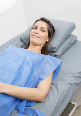 Female Patient In Protective Clothing Lying On Hospital Bedの写真素材