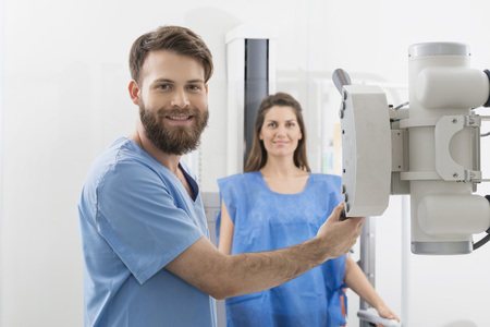 Radiologist Adjusting X-ray Machine Over Female Patient In Hospiの写真素材