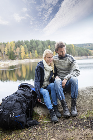 Couple With Backpack Relaxing On Lakeshore During Campingの写真素材