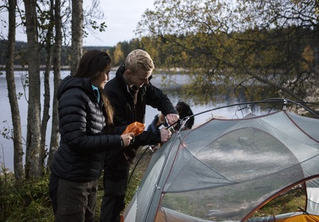 Young Couple Setting Up Tent By Lakeの写真素材