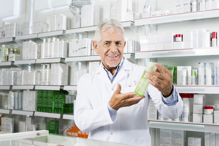 Confident Pharmacist Smiling While Holding Product In Pharmacyの写真素材
