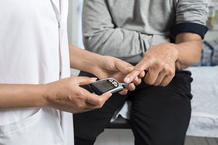 Female Doctor Examining Sugar Level Of Patient With Glucometerの写真素材