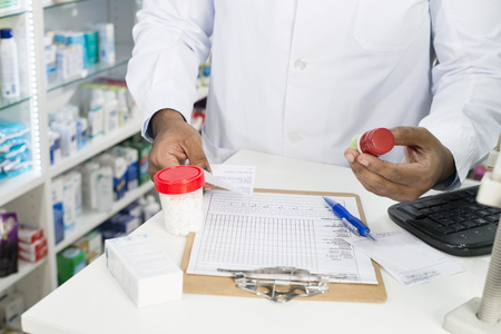 Pharmacist With Pill Bottles And Clipboard At Counterの写真素材
