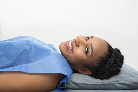 Female Patient Smiling While Lying On Bed In Clinicの写真素材
