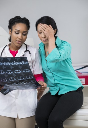 Doctor Showing X-ray Report To Tensed Woman In Examination Roomの写真素材