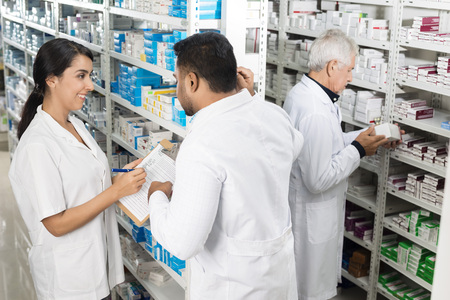 Pharmacists Working By Shelves In Pharmacyの写真素材
