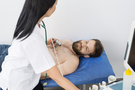 Doctor Examining Male Patient With Ultrasound Machineの写真素材