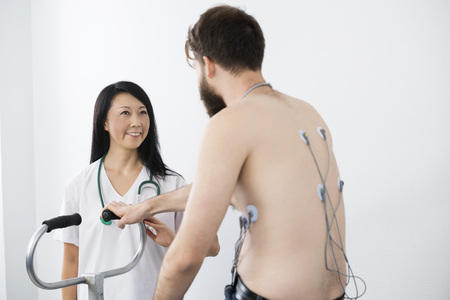 Doctor Looking At Patient Cycling With Electrodes Attached On Baの写真素材