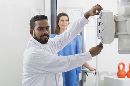 Radiologist Adjusting X-ray Machine Over Patient In Hospitalの写真素材