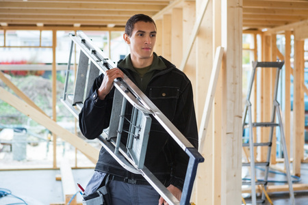 Carpenter Carrying Ladder At Construction Siteの写真素材
