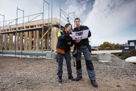 Carpenters Discussing About Plan Against Incomplete Buildingの写真素材